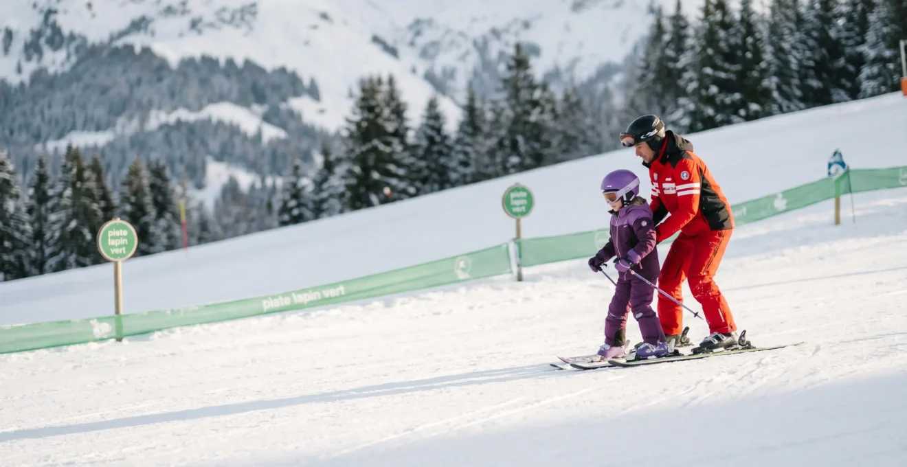Un enfant apprenant le ski sur une piste adaptée à Morzine avec son moniteur.